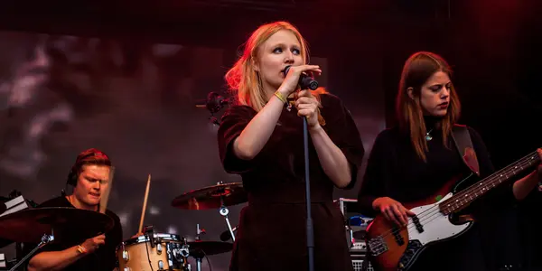 Tre personer sjunger och spelar musik på scen